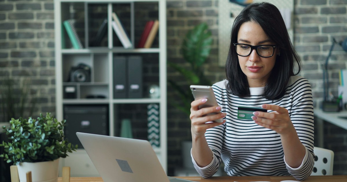 Mujer comprando por internet con el móvil y una tarjeta en la mano