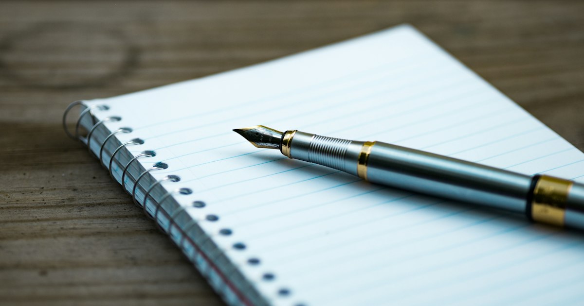 Cuaderno abierto con una pluma estilográfica encima
