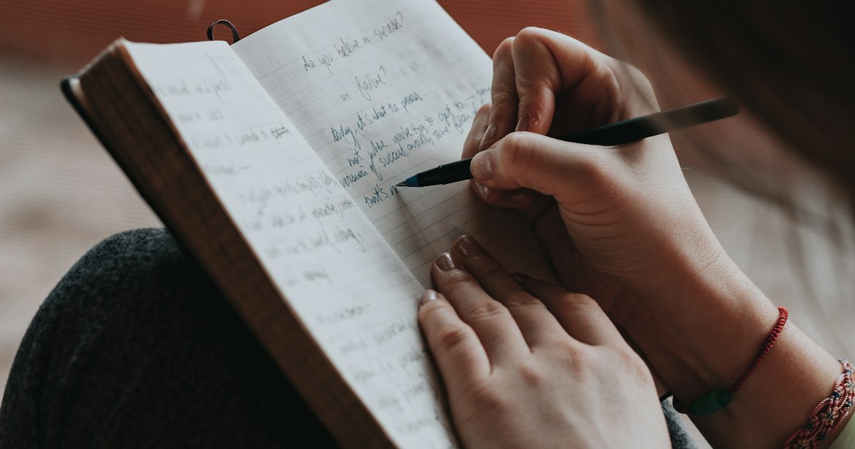 Persona escribiendo a mano en un cuaderno