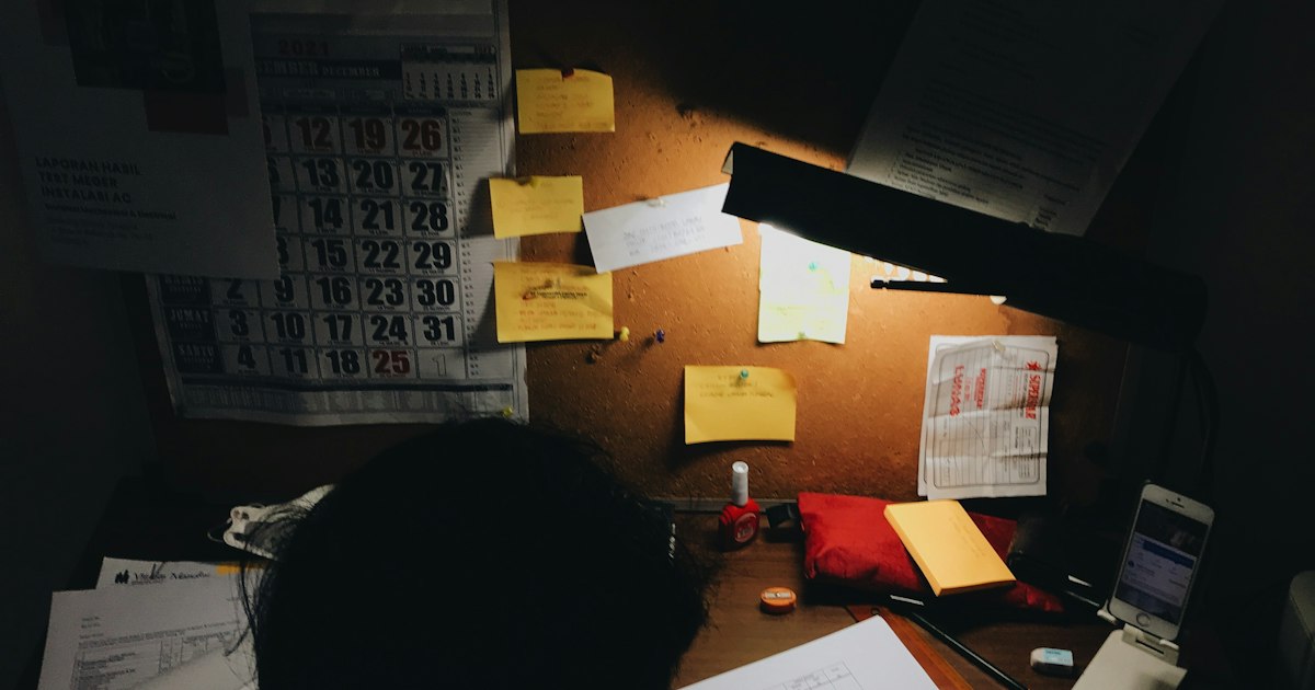 Pared con un calendario y notas adhesivas sobre un escritorio en penumbra