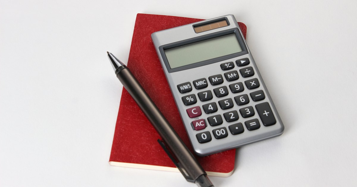Calculadora y bolígrafo sobre una libreta roja