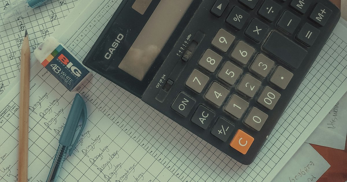 Calculadora, lápiz y bolígrafo sobre papel cuadriculado