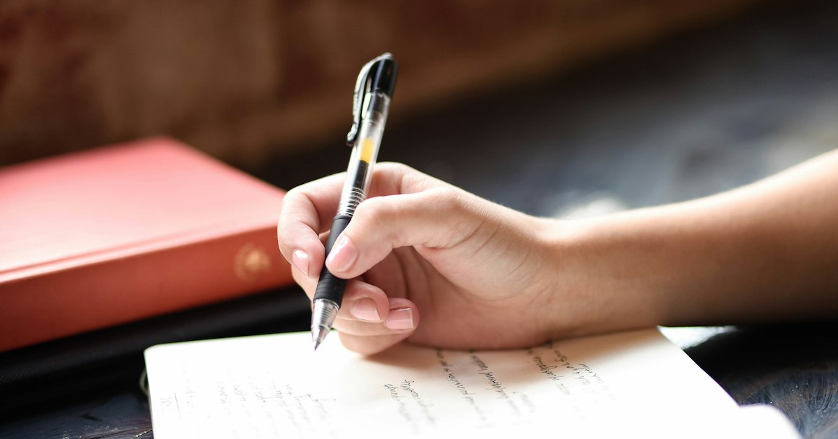 Mano escribiendo con un bolígrafo en una hoja