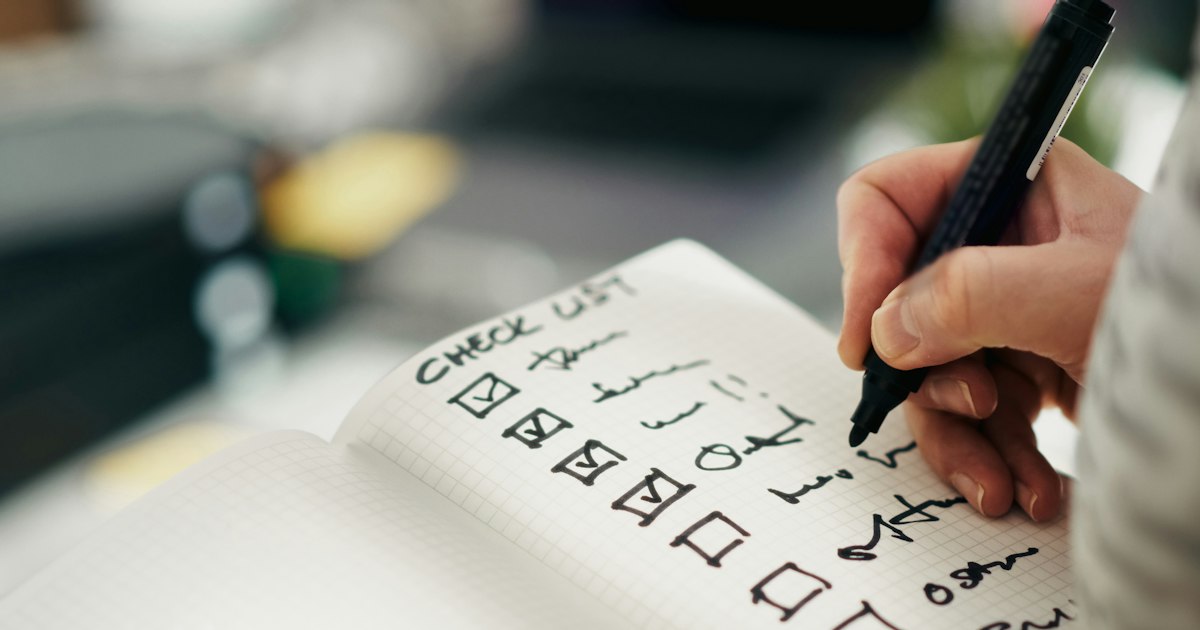 Mano marcando una lista de tareas en un cuaderno