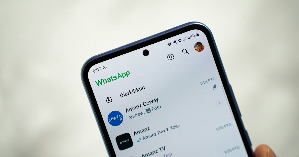 Mano sujetando un móvil con la lista de chats de WhatsApp