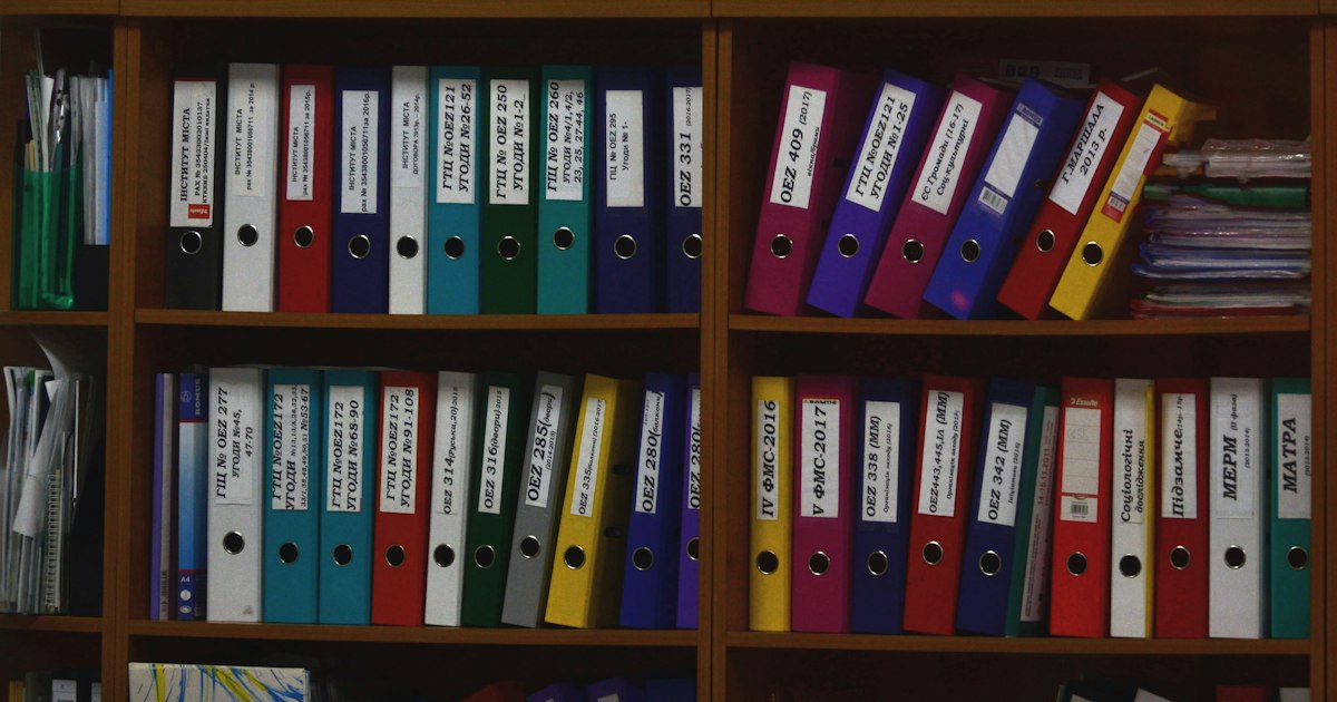 Archivadores de colores ordenados en una estantería