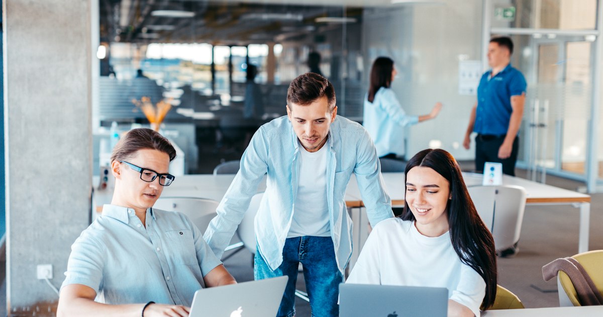Equipo trabajando junto delante de varios portátiles en una oficina